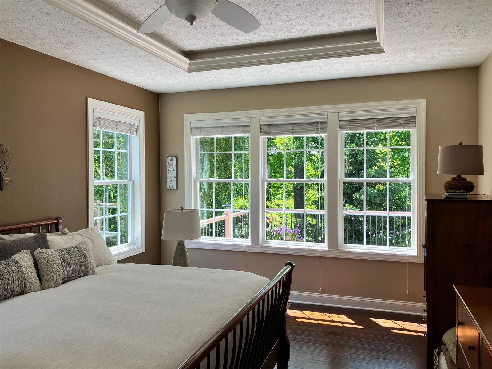 Sunlit bedroom with freshly cleaned windows looking out on green trees